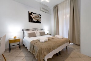 A hotel room with a bed, a nightstand, a chair, and a painting on the wall. - Holiday Home 'Grace’s Garden - Cagliari' (Cagliari)