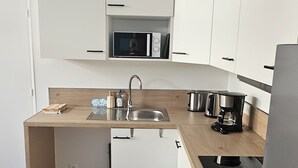 A modern kitchen with white cabinets, a stainless steel sink, and a built-in oven. - Vrbo Property (Thury-Harcourt-le-Hom)