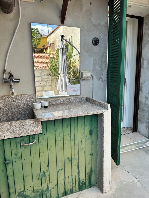 A kitchen area with a green wooden cabinet, a sink, and a wall-mounted picture.
