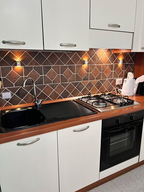 A modern kitchen with a gas stove, a sink, and a coffee maker.
