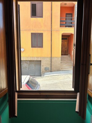 A view through a window of a building with a staircase leading to a balcony.