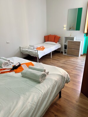 A hotel room with two beds, a bedside table, a dresser, and a mirror.
