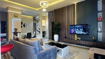 A modern living room with a grey sofa, a coffee table, and a TV mounted on the wall.
