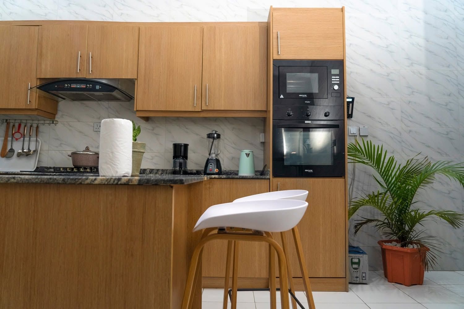 Eine moderne Küche mit Holzschränken, einem Einbauofen und einer Kaffeemaschine.