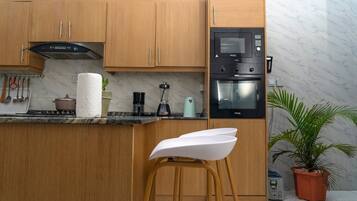 Eine moderne Küche mit Holzschränken, einem Einbauofen und einer Kaffeemaschine.