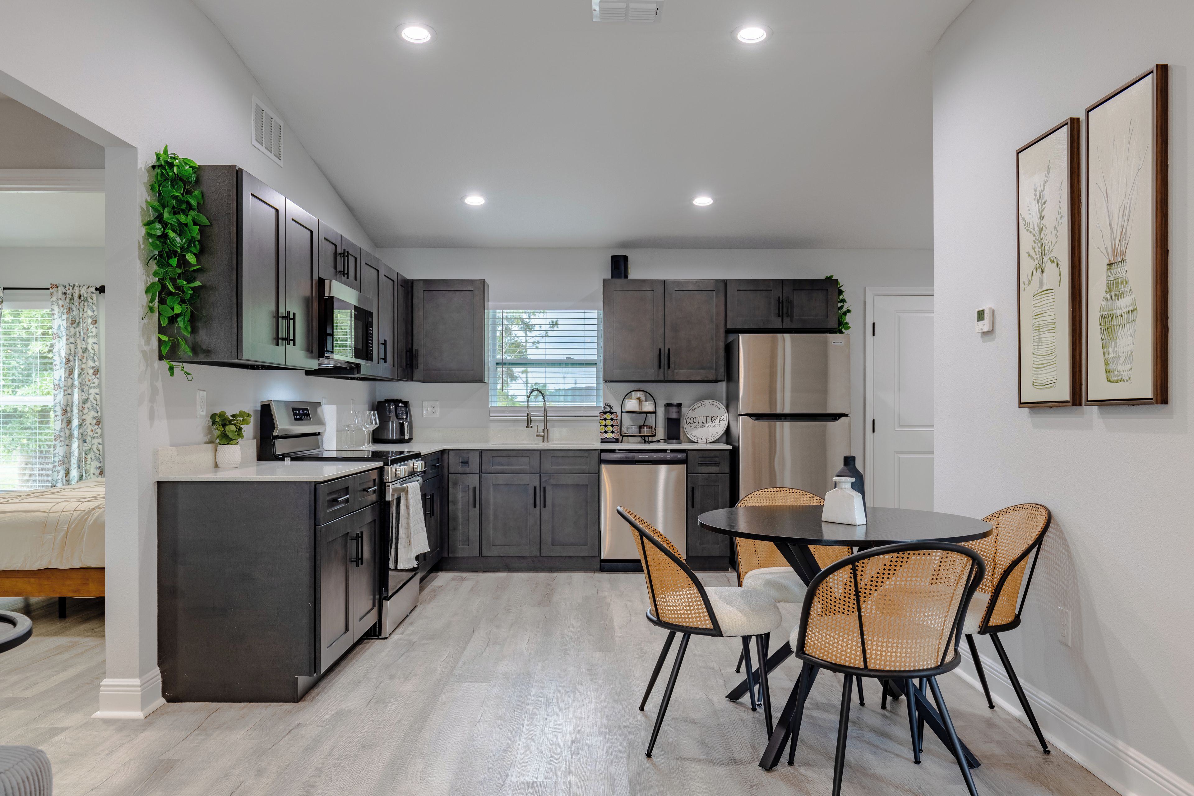 Una cucina moderna con mobili scuri, elettrodomestici in acciaio inossidabile e una zona pranzo con sedie in vimini.