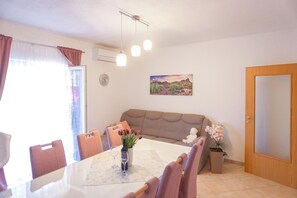 Ein Essbereich mit Tisch, Stühlen, einer Vase mit Blumen und einem Bild an der Wand.