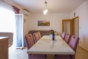 Ein Esszimmer mit einem langen Tisch, sechs Stühlen, einer Blumenvase und einem Gemälde an der Wand.