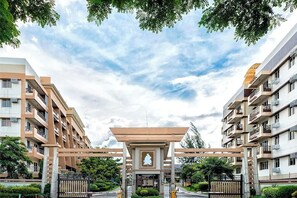 A residential building with a central entrance gate, surrounded by greenery and other buildings. - Modern 1BR Executive Suite in Taguig near BGC (Taguig)