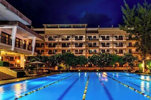 A hotel with a swimming pool, multiple balconies, and a well-lit exterior. - Modern 1BR Executive Suite in Taguig near BGC (Taguig)
