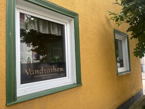 A building facade with a window displaying the name 'Vandrarhem' and a website address.