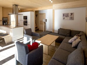Ein stilvoller Wohnraum mit einer Küche, grauen Sofas, einem Holztisch und einer Wand mit herzförmigen Dekorationen.