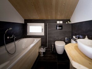 Ein modernes Badezimmer mit einer freistehenden Badewanne, einer Toilette und einem Waschbecken.