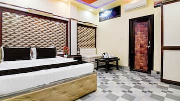 Una habitación de hotel con una cama, una mesita con un jarrón de flores, un sofá y una puerta con panel texturizado.