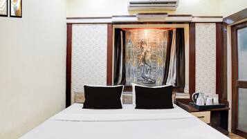 A hotel room with a bed, a nightstand, an air conditioning unit, and a curtain with a painting.