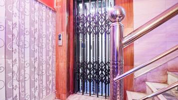 Uma escadaria com corrimão de metal e uma porta decorativa com grade metálica.