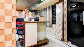 A reception area with a counter, a chair, a decorative vase, and a patterned wall.