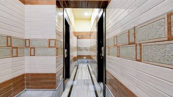 A corridor with tiled walls, a marble floor, and wooden accents.