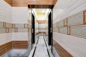 Un pasillo con paredes de azulejos, piso de mármol y detalles de madera.