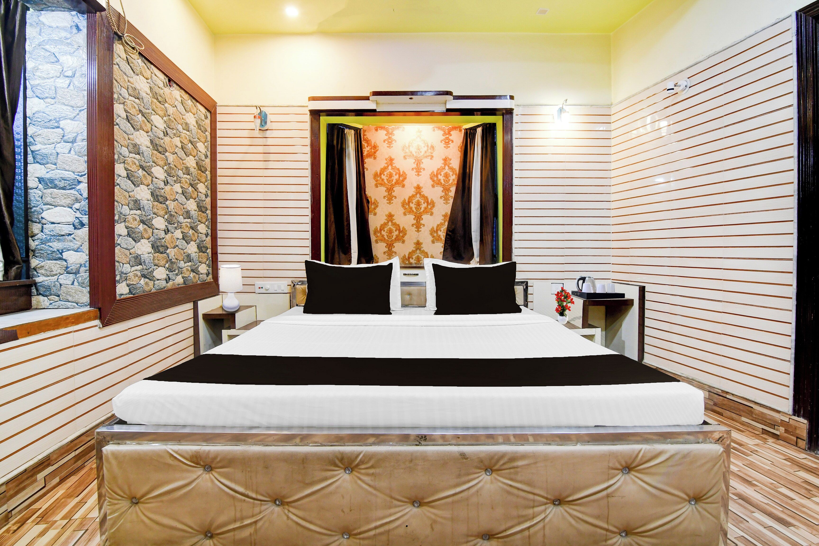 Habitación de hotel con una cama grande, una pared de piedra y un suelo de madera.