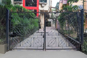 Una entrada protegida con una reja metálica decorada con motivos de hojas.