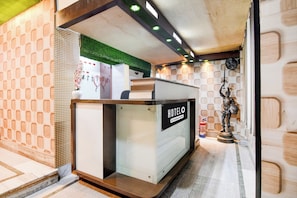 A reception desk with a 'HOTEL' sign, a fire extinguisher, and a statue.