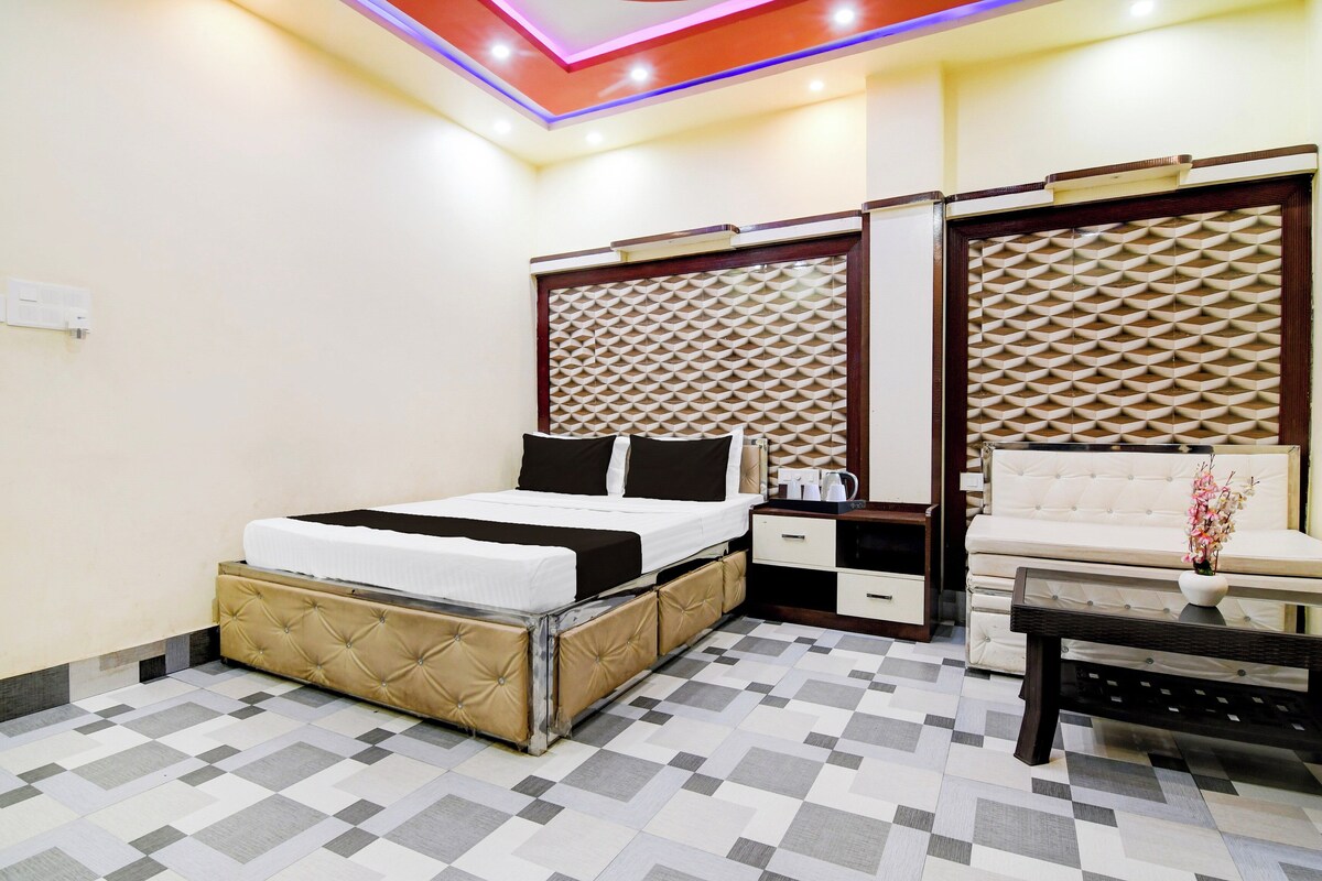 Una habitación de hotel con cama, mesitas de noche, un sofá y un panel decorativo en la pared.