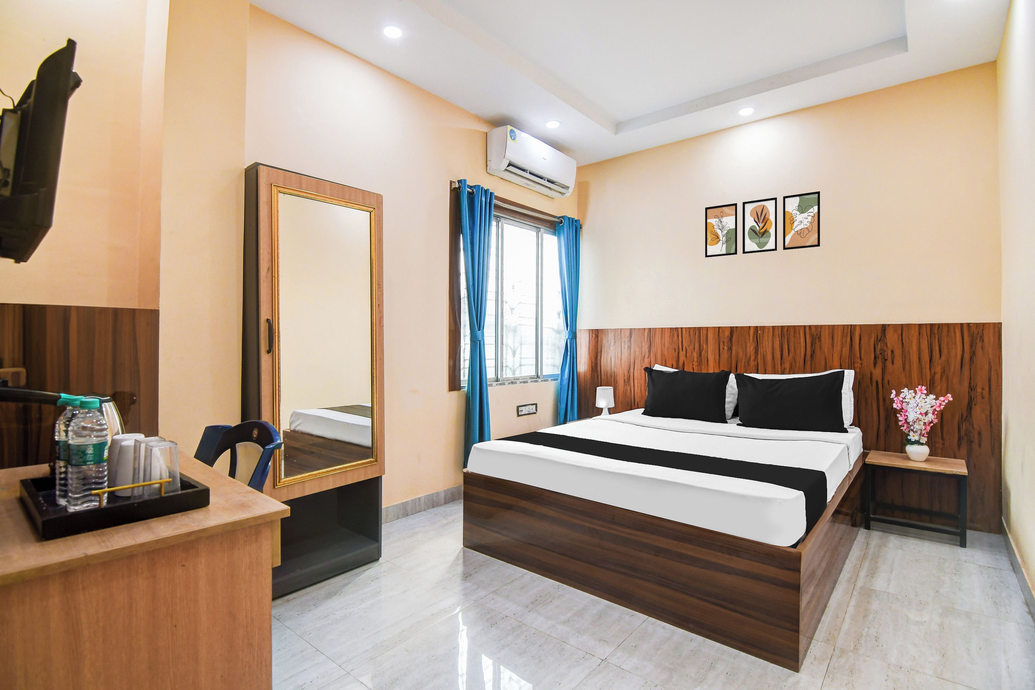 A hotel room with a bed, bedside table, mirror, and a window with curtains.