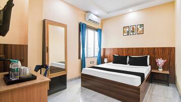 A hotel room with a bed, bedside table, mirror, and a window with curtains.