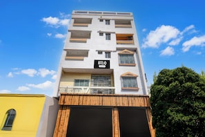 A multi-story hotel building with a sign indicating it is a company-serviced hotel. - Hotel O DumDum Thana More Formerly Bimla (Barakpur)