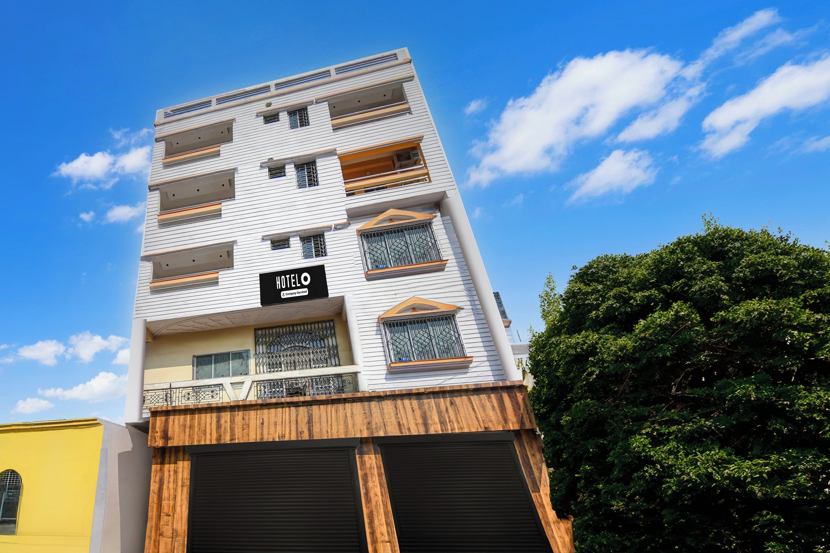 A multi-story hotel with a modern facade, balconies, and a sign indicating it is a company-serviced hotel.