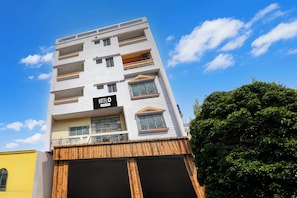 Un hotel de varios pisos con fachada moderna, balcones y un letrero que indica que es un hotel de servicios corporativos.