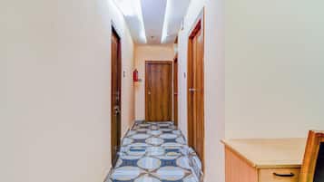 Un couloir avec des carreaux de sol à motifs, des portes en bois et un petit bureau doté de tiroirs.
