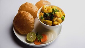 Ein Teller mit Speisen, darunter Brötchen und eine Schüssel gewürfelte Kartoffeln mit Kräutern.