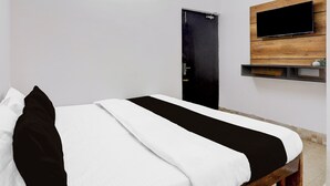 Ein Hotelzimmer mit einem Bett, einem flachbildfernseher an der Wand und einer Tür.