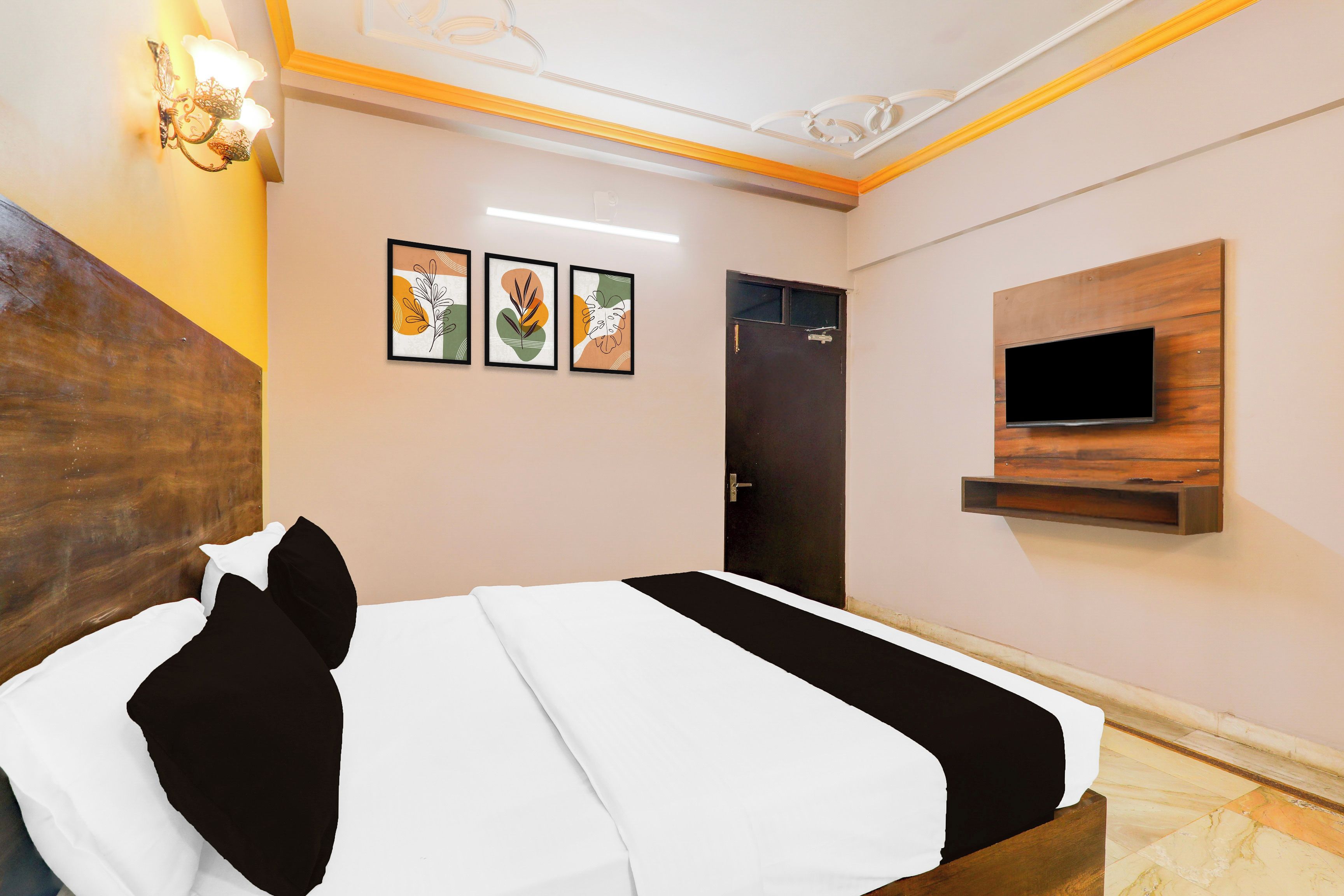 Habitación de hotel con una cama, un televisor montado en la pared y tres obras de arte enmarcadas.