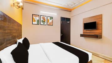 Habitación de hotel con una cama, un televisor montado en la pared y tres obras de arte enmarcadas.