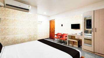 Una habitación de hotel con cama, escritorio, silla, televisor y armario.