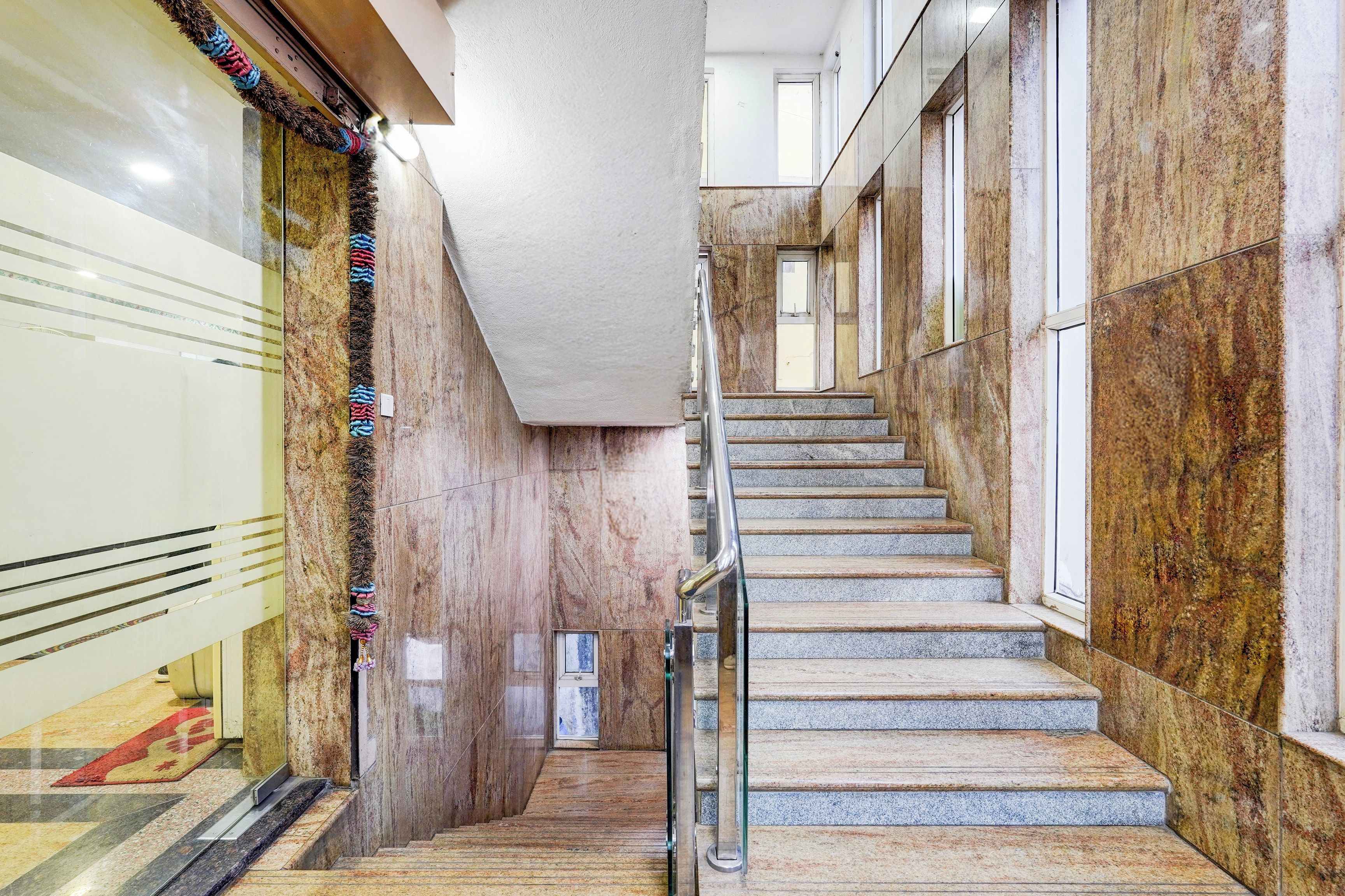 A marble staircase with a metal handrail, leading to a landing with a door.