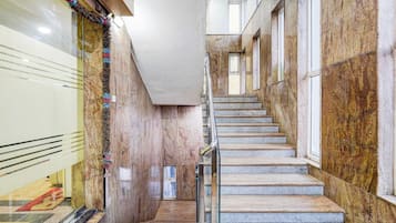 A marble staircase with a metal handrail, leading to a landing with a door.