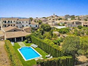 A residential area with a swimming pool, lounge chairs, and a well-maintained garden. - Holiday Home in Llubi With Swimming Pool (Llubi)