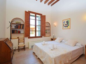 A bedroom with a bed, a bookshelf, a window, and a painting on the wall. - Holiday Home in Llubi With Swimming Pool (Llubi)