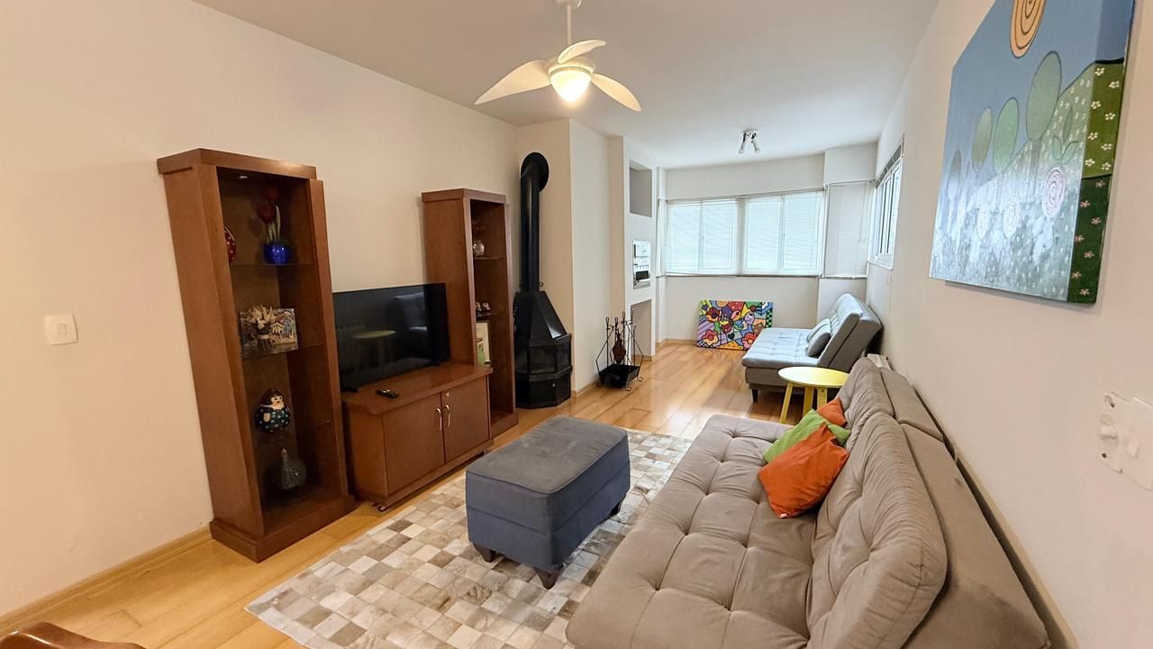 A living room with a sofa, ottoman, TV, and wooden cabinets.