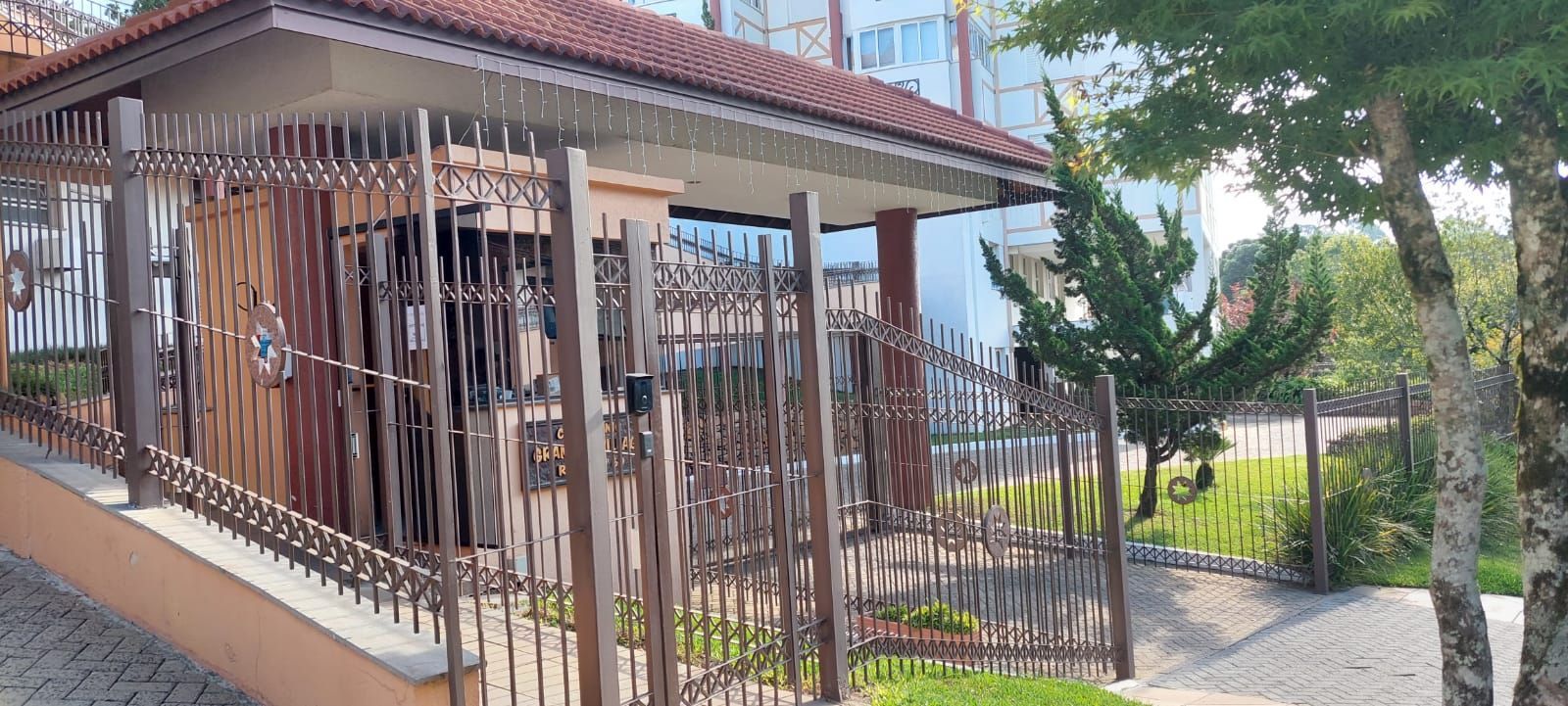 A gated residential area with a covered entrance, a paved pathway, and a small garden.