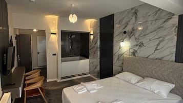 A modern hotel room with a large bed, a desk, and a seating area.