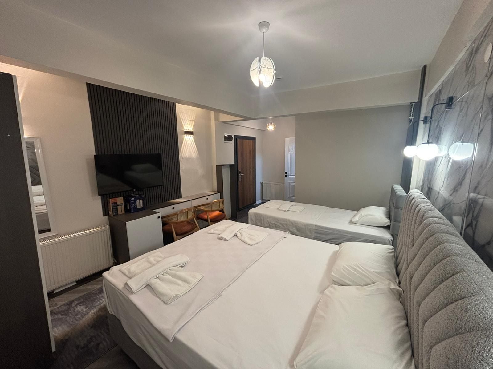 Een hotelkamer met twee bedden, een televisie, een bureau met stoel en een spiegel.