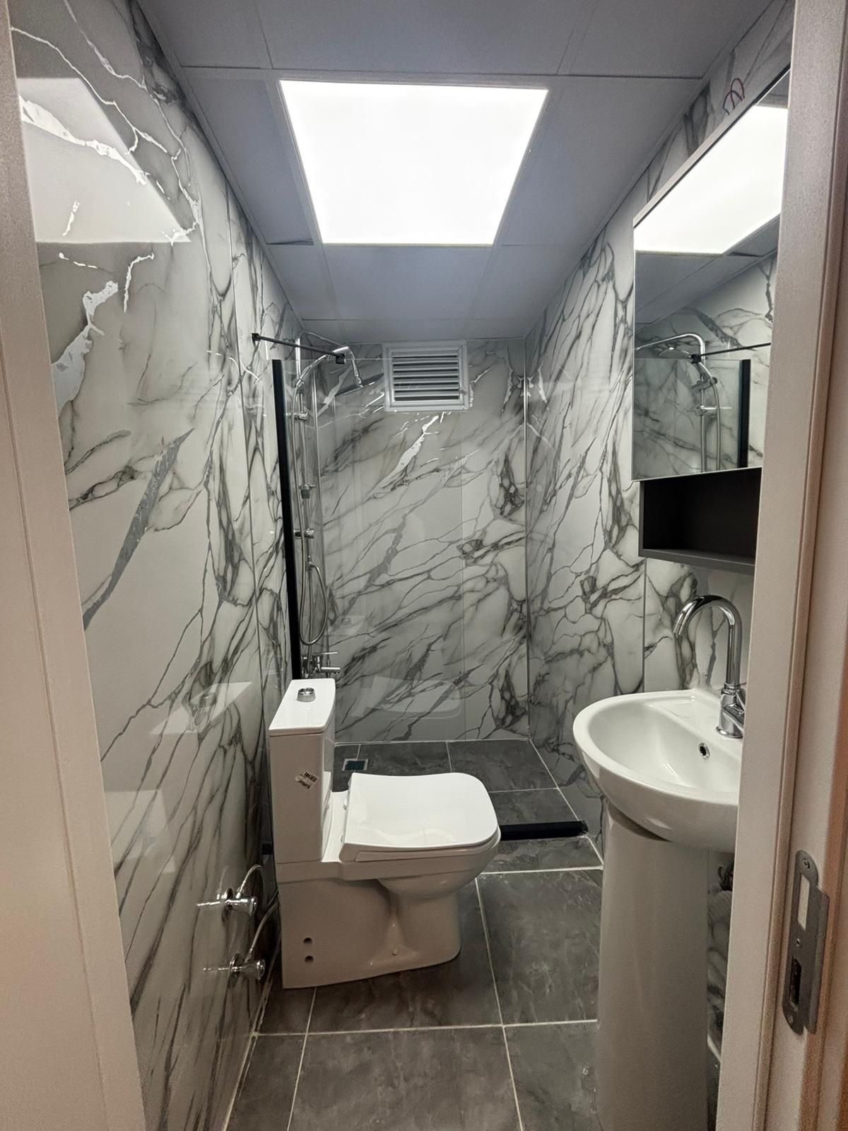 Un baño con inodoro, lavamanos y ducha.