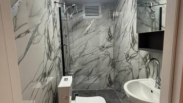 Un baño con inodoro, lavamanos y ducha.