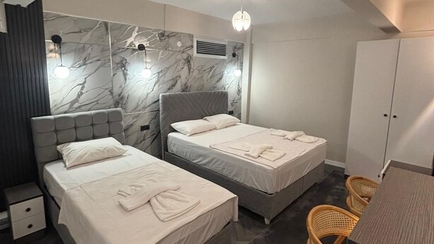 A hotel room with two beds, a wardrobe, a desk, and a chair. - Klas Otel (Karasu)