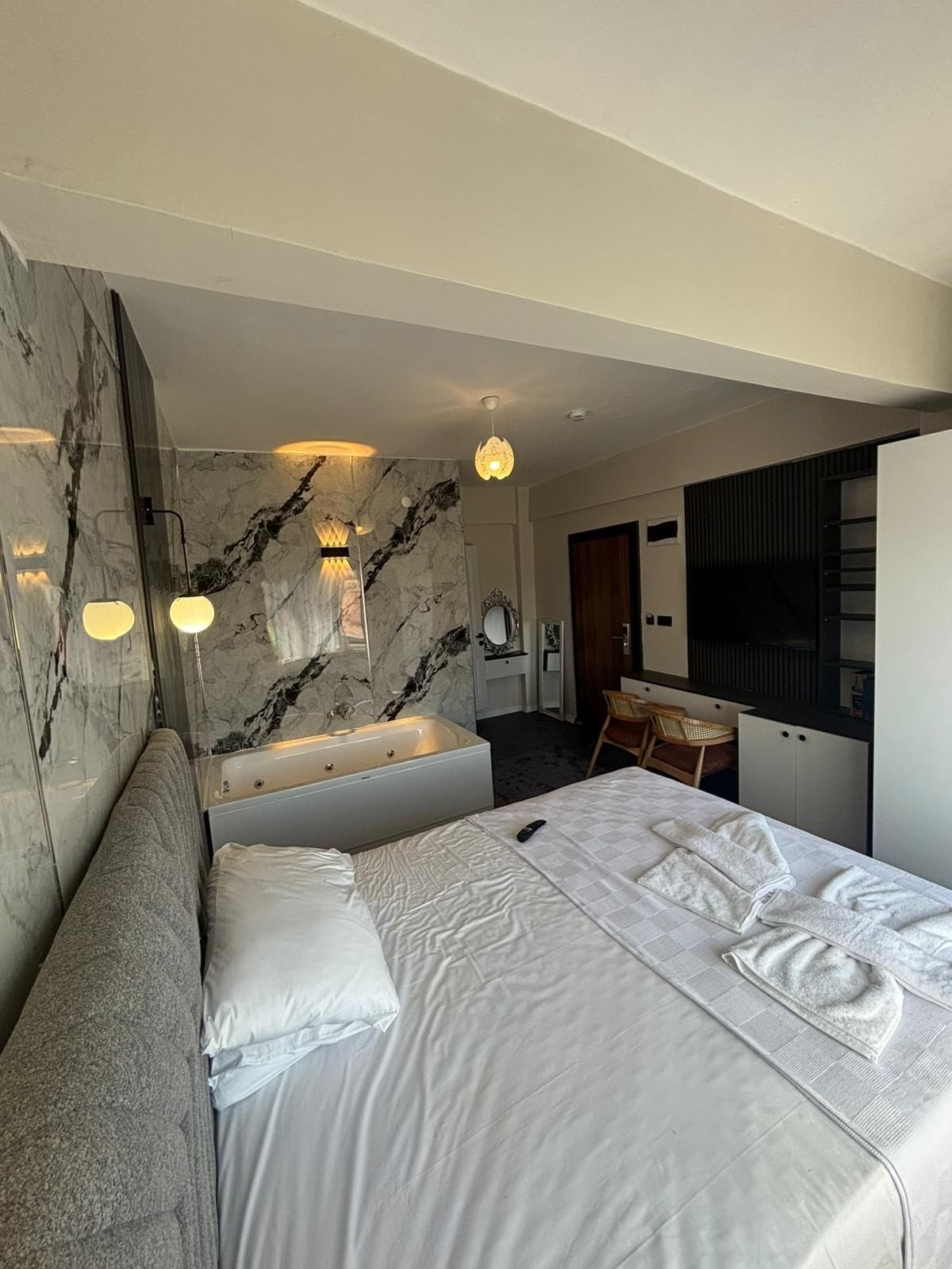 Une chambre d’hôtel moderne dotée d’un grand lit, d’une salle de bain séparée avec baignoire, d’un bureau et d’une chaise.